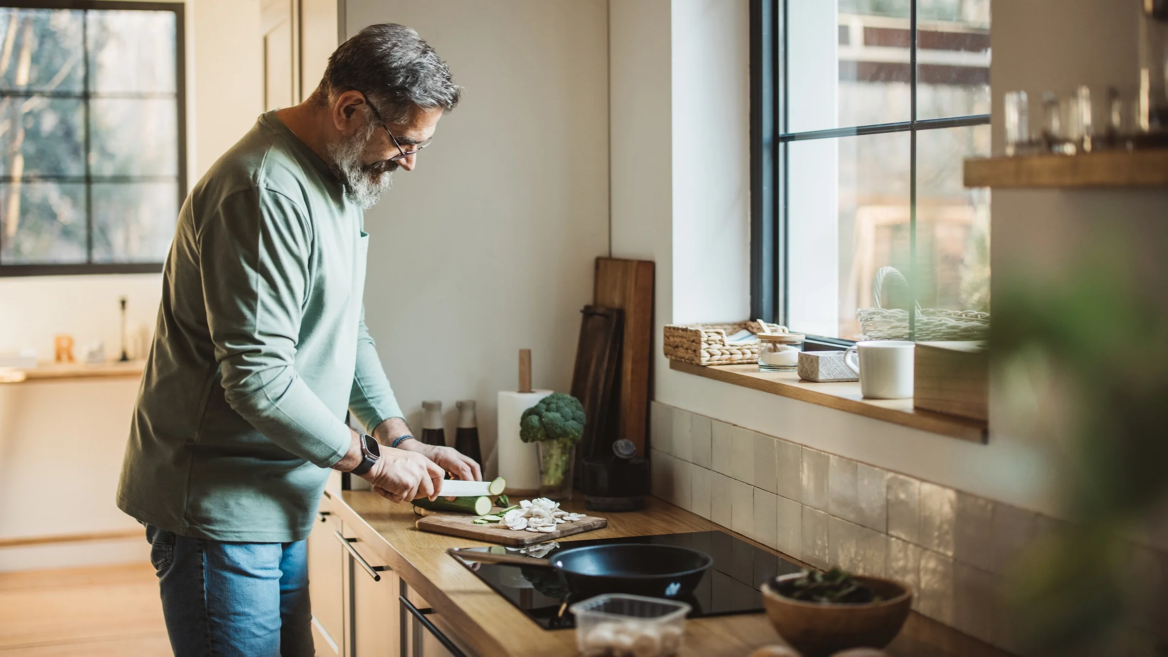 A man chops vegetables in the kitchen.