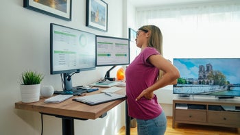 movement-exercise: woman working with back pain at standing desk 1370674740