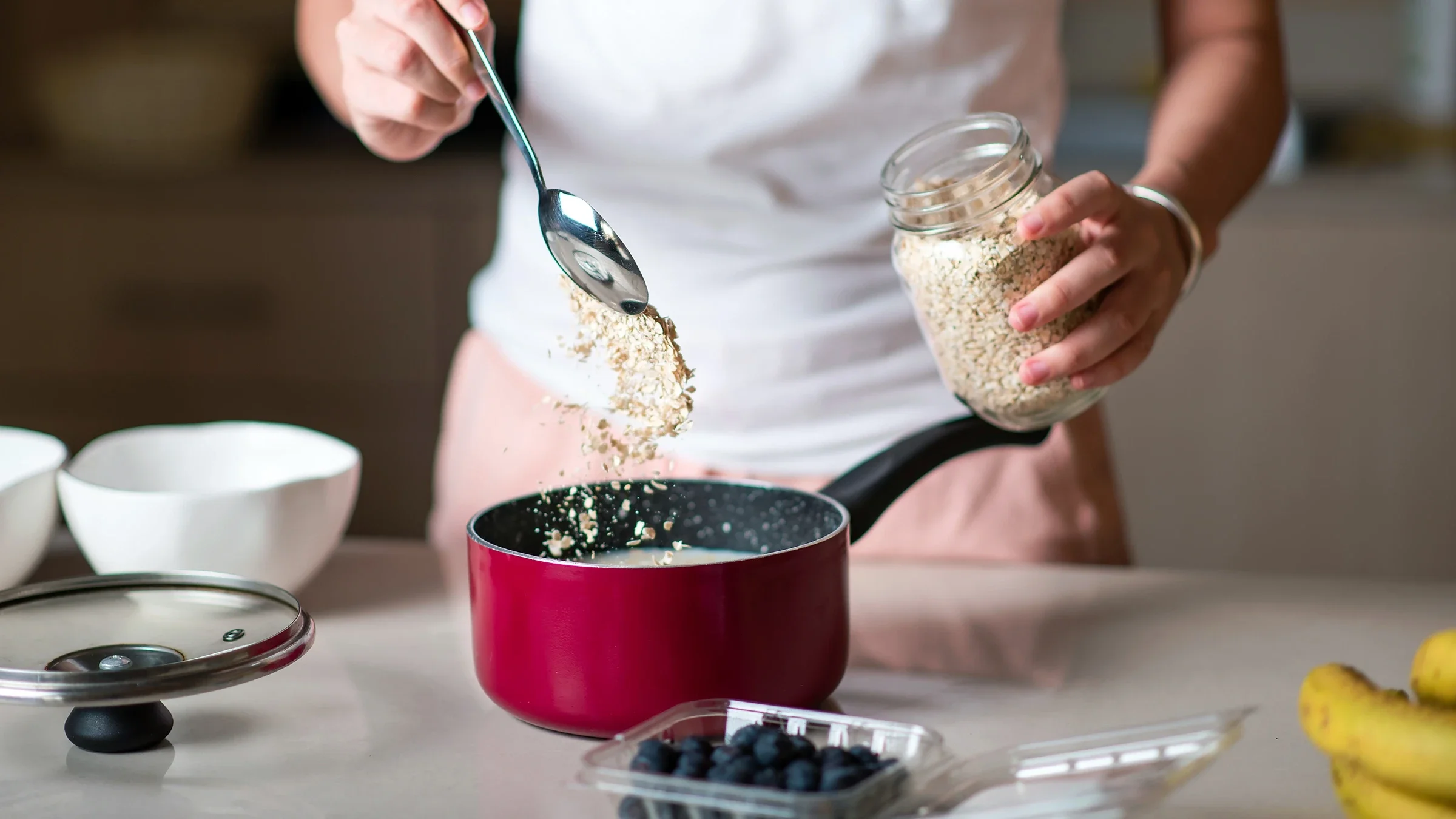 A woman puts oatmeal into a pot. 