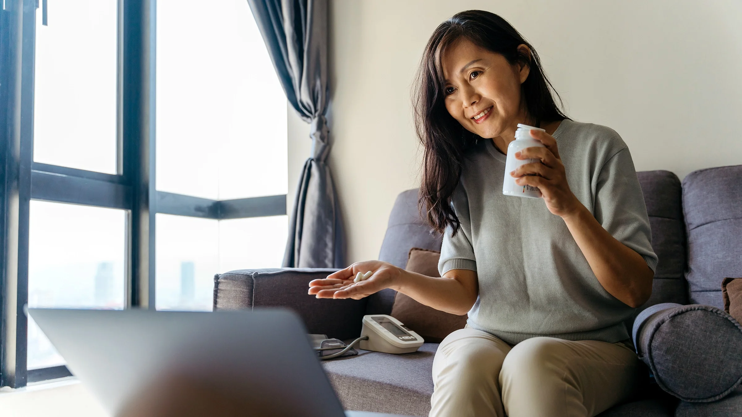 A woman uses a laptop at home for a telehealth appointment with her doctor.