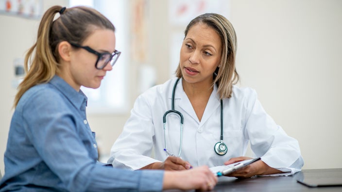 A doctor discusses healthcare information with a young female patient.