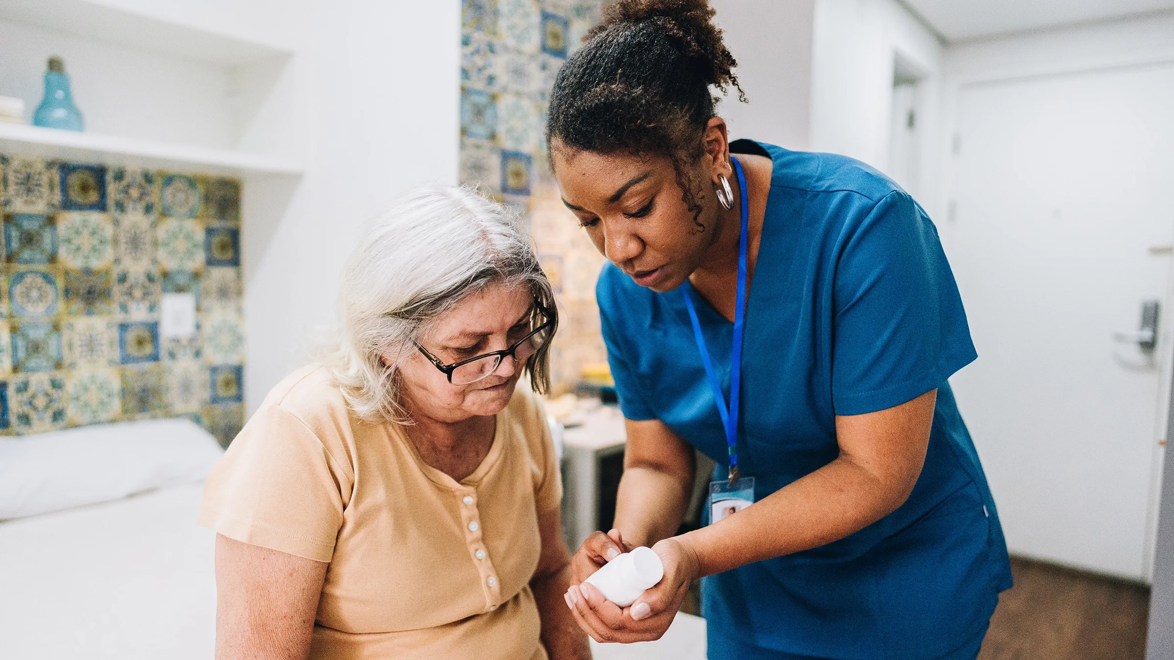 A healthcare professional is discussing medication with an older woman.