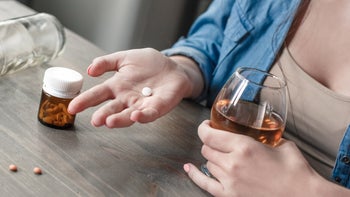 Antipsychotics: Alcohol: holding pill and wine glass-1145351382
