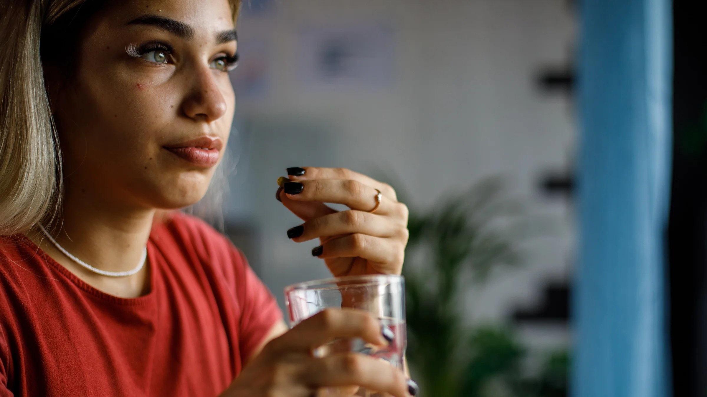 A woman prepares to take medication with a glass of water.
