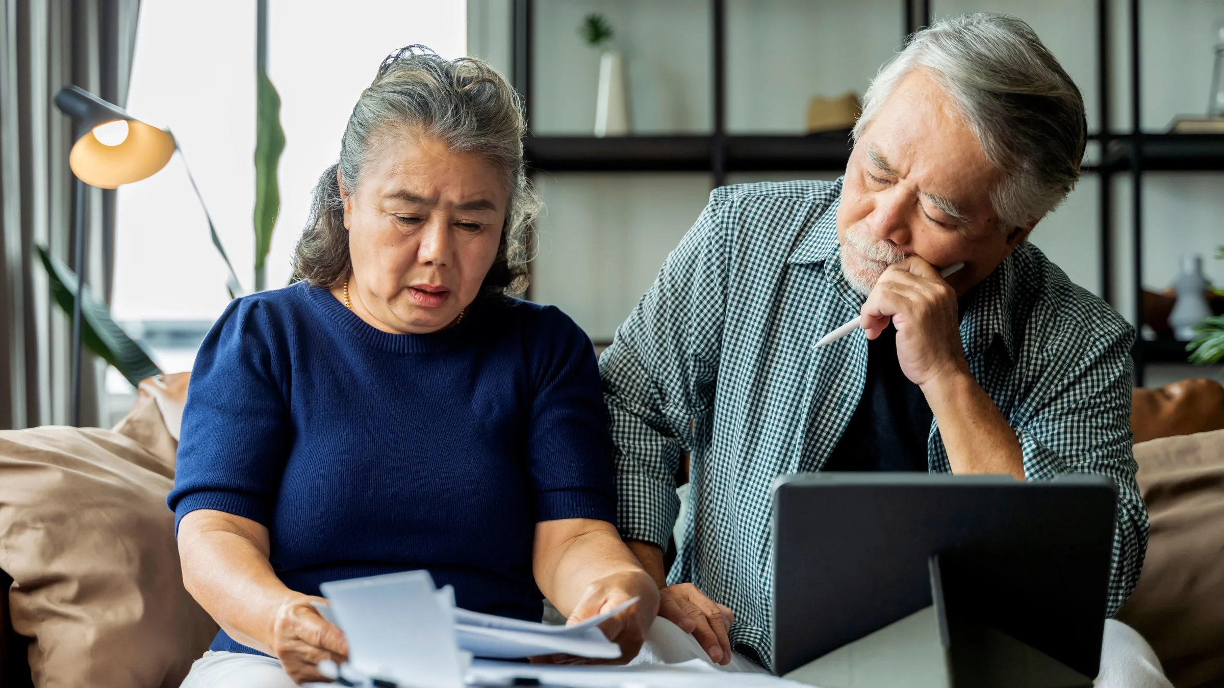 A senior couple appears stressed as they look at bills.