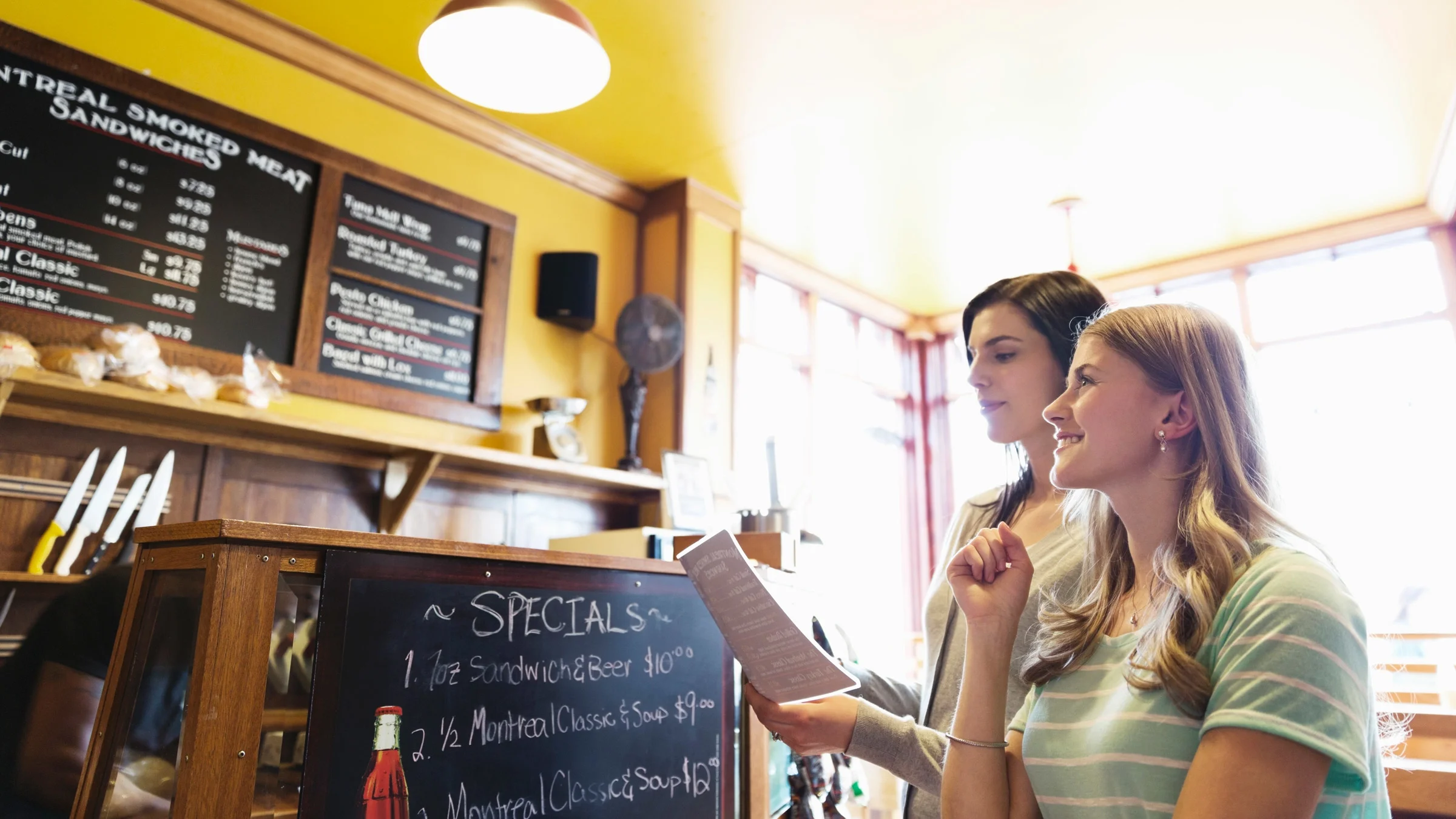 Two people looking at a deli menu.