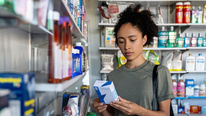A woman reads a package label at the drugstore.