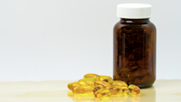 Supplement bottle and yellow gel capsules in a pile on a white background.
Fahroni/iStock via Getty Images