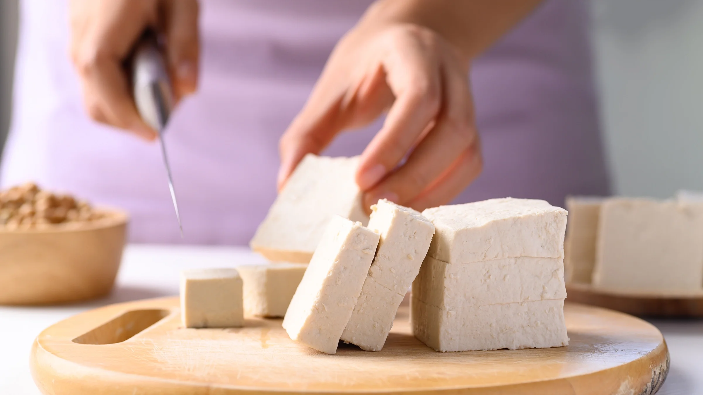 Close-up hands slicing tofu.