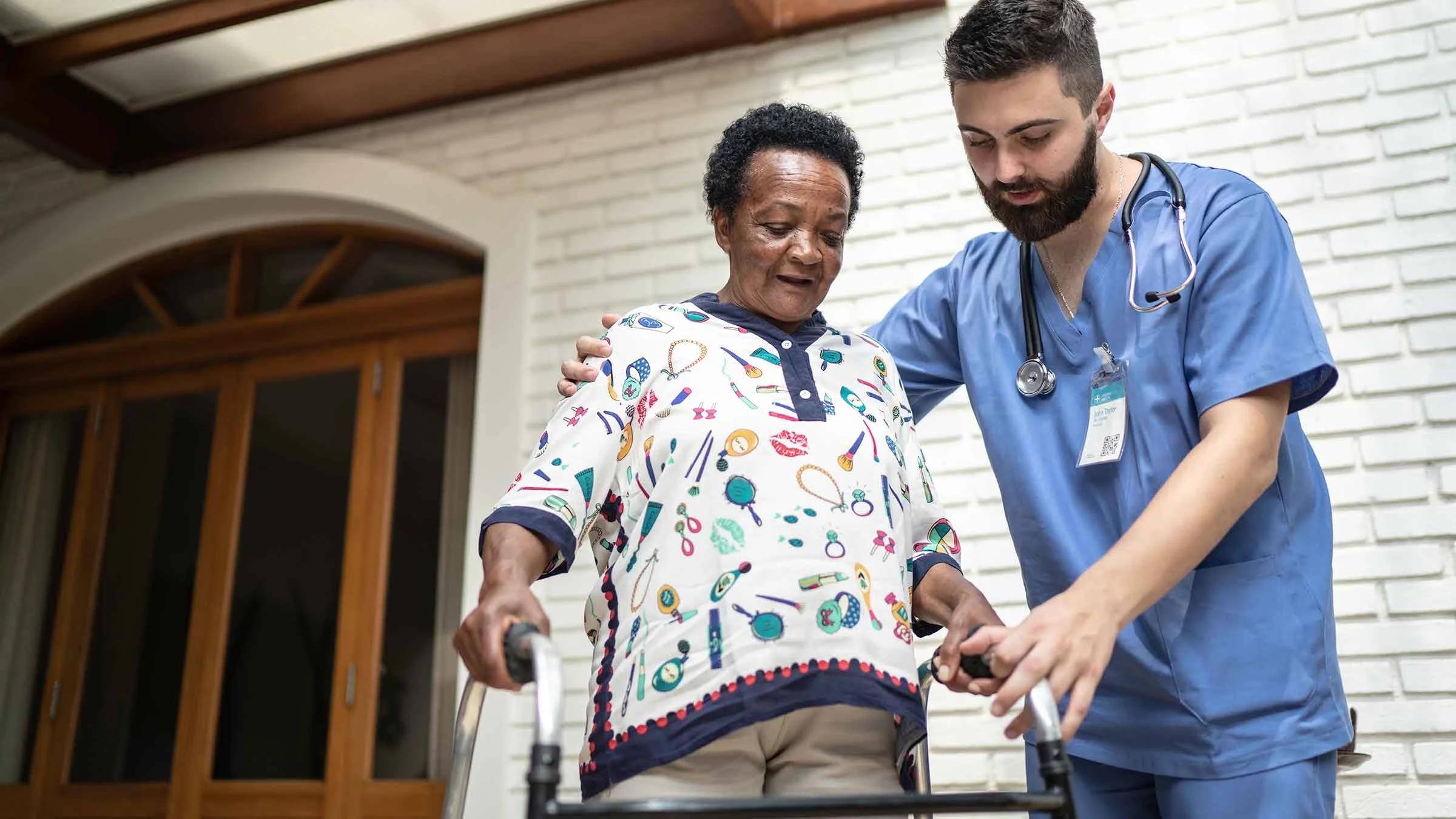 A home caregiver helps a senior woman to walk.