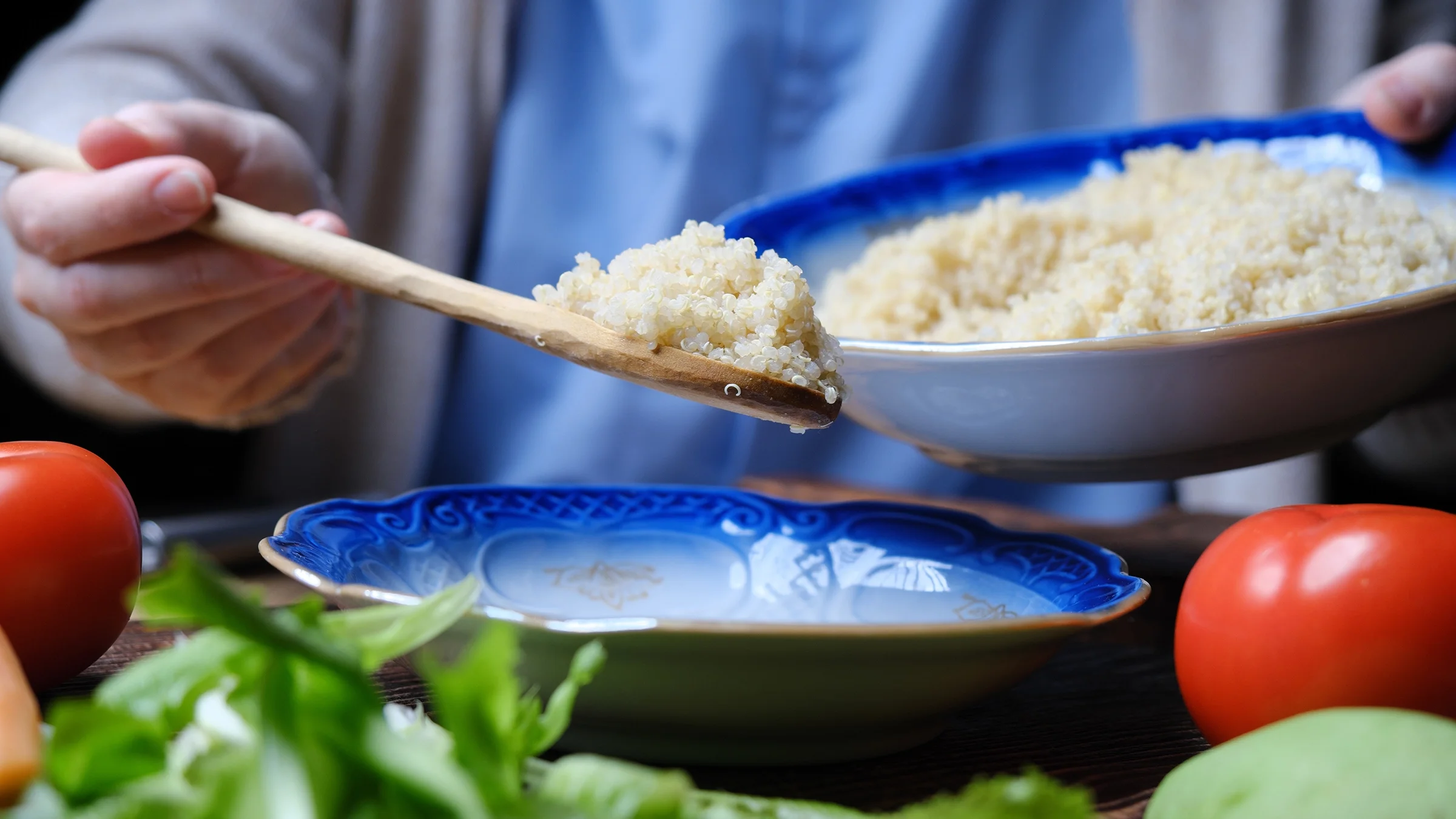 A person scoops up a serving of quinoa from a bowl. 