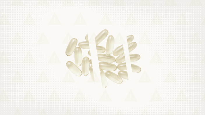 Off white background with texture and warning sign pattern. In the center is a pile of white soft gel capsule pills cut into thirds. 