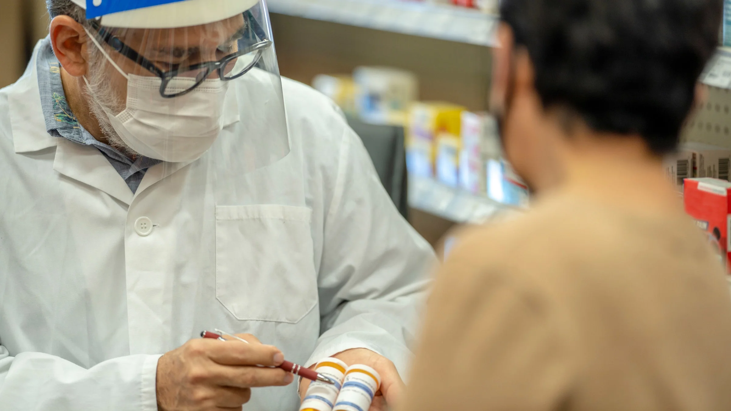 A pharmacist explaining two pill bottles to a patient.
