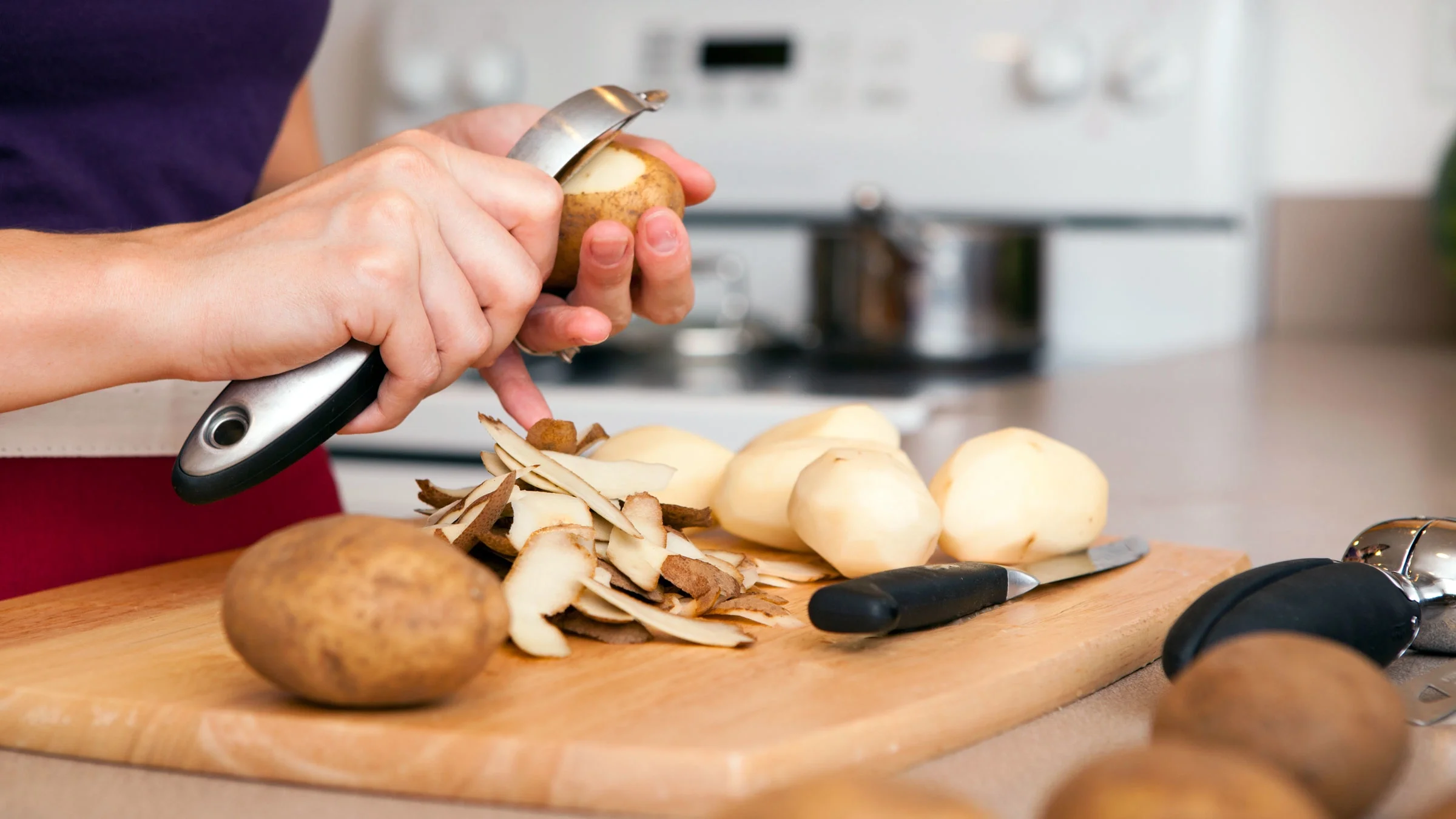 Close-up of a woman peeling potatoes.