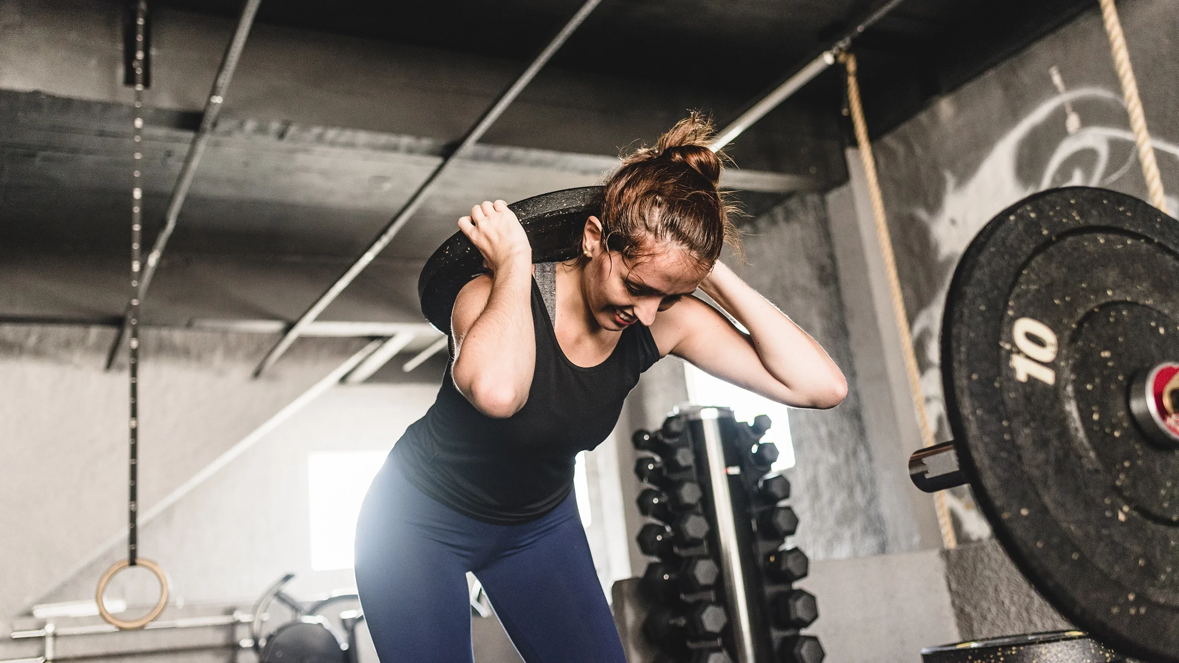 Woman lifting weight plate in the gym