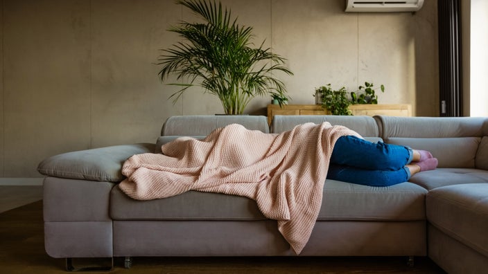 Someone curled up in a blanket on their couch.