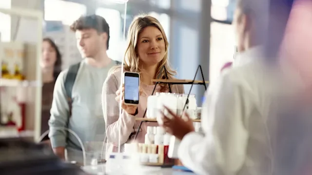 Savings: woman using mobile phone at pharmacy 2249492027