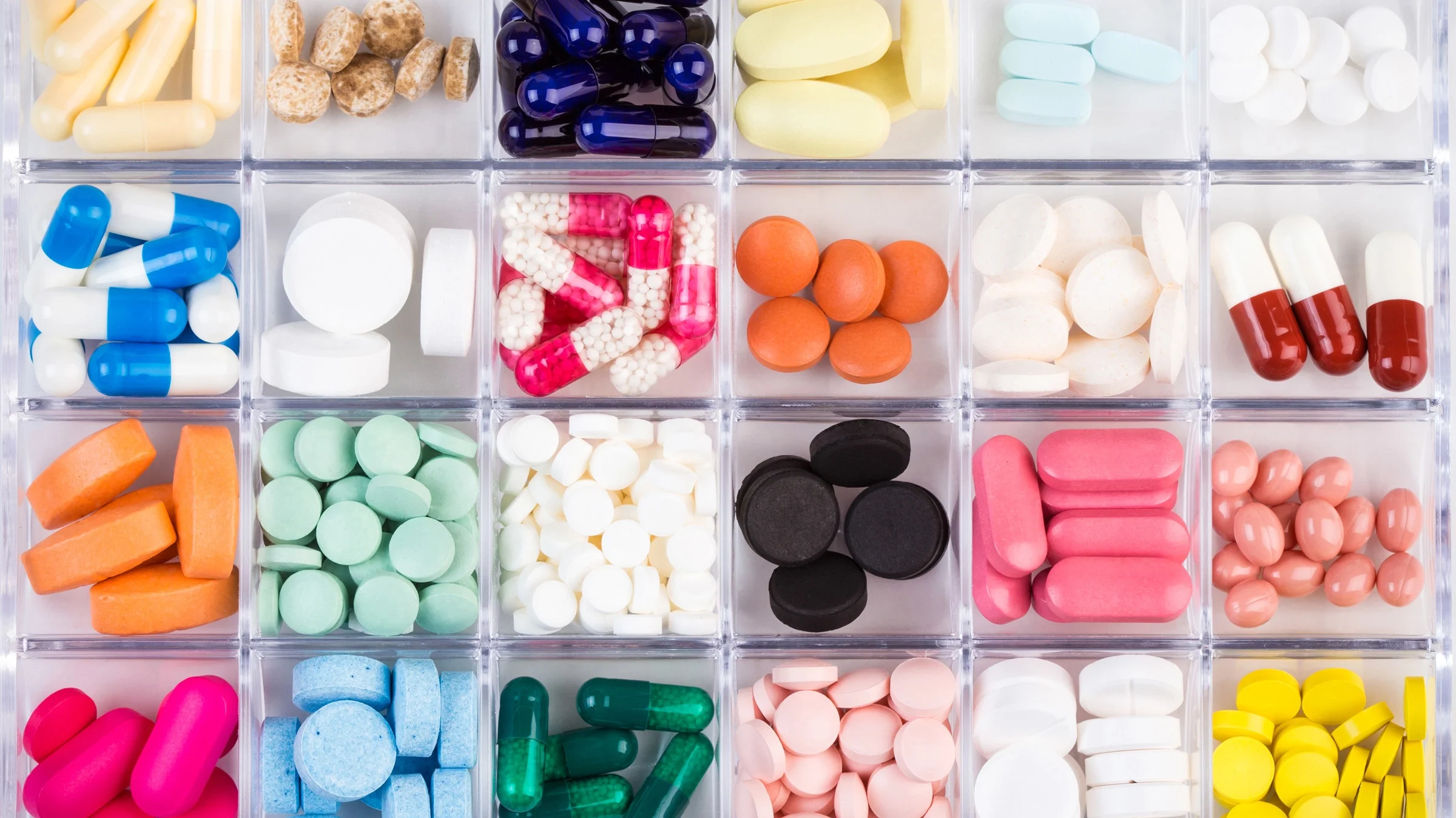 A variety of colorful pills laid out in an organizer.