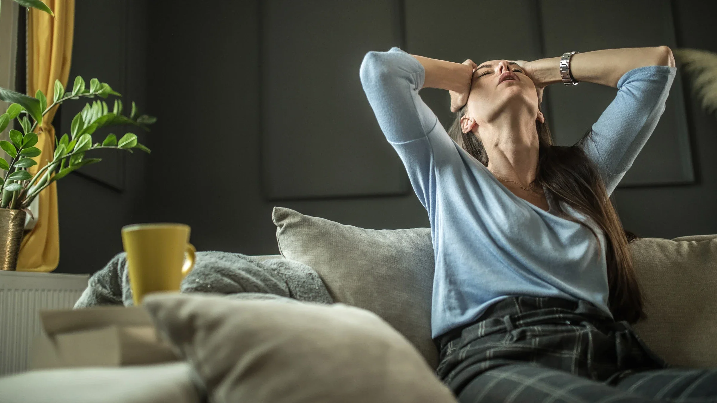 A person sitting on their couch, holding their head back.
zeljkosantrac/E+ via Getty Images 