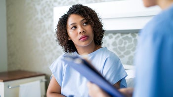 kidneys: woman in a hospital gown speaking to a medical professional 981468200