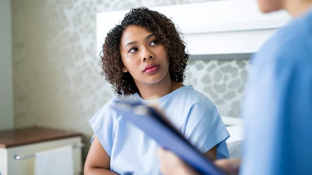 kidneys: woman in a hospital gown speaking to a medical professional 981468200