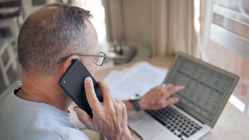 Health: Patient Advocacy: senior man on phone reviewing computer screen 1329694321