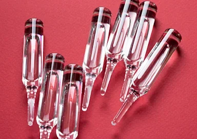 Close-up of seven sealed vaccine vials on a red background.
VITAL MIZHYHURSKI/iStock via Getty Images
