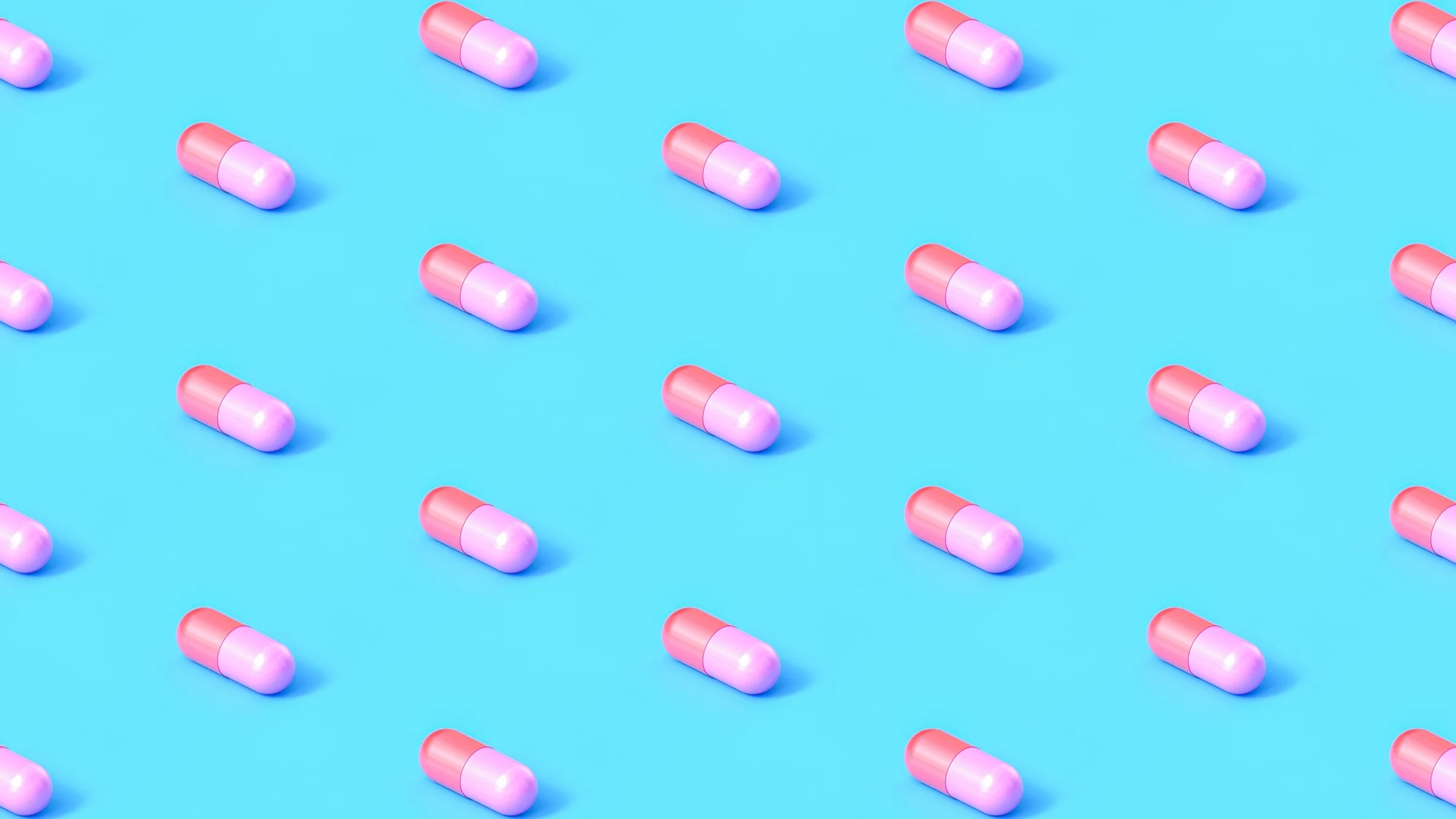 Red and pink capsule pills lined up in a diagonal pattern on a light blue background.