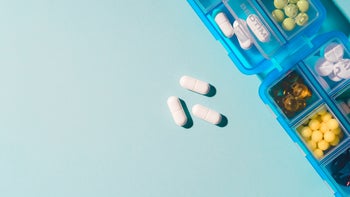 Health: Medication Education: pill organizer and pills light blue background-1217356953