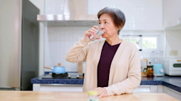 Senior woman takes medicine with a glass of water in the kitchen of her home.
PonyWang/E+ via Getty Images 