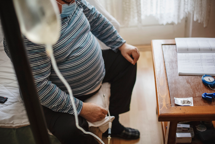 Cropped shot of a man sitting on his couch next to the coffee table hooked up to an at-home dialysis machine.