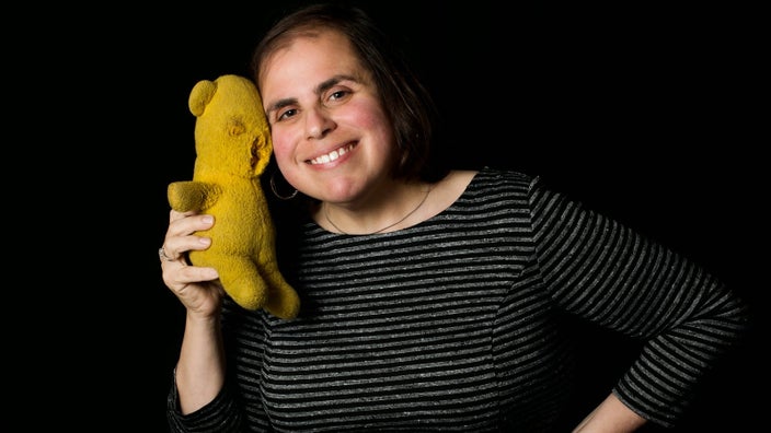 Allison Landa is pictured as an adult with a well-loved stuffed bear from her childhood.