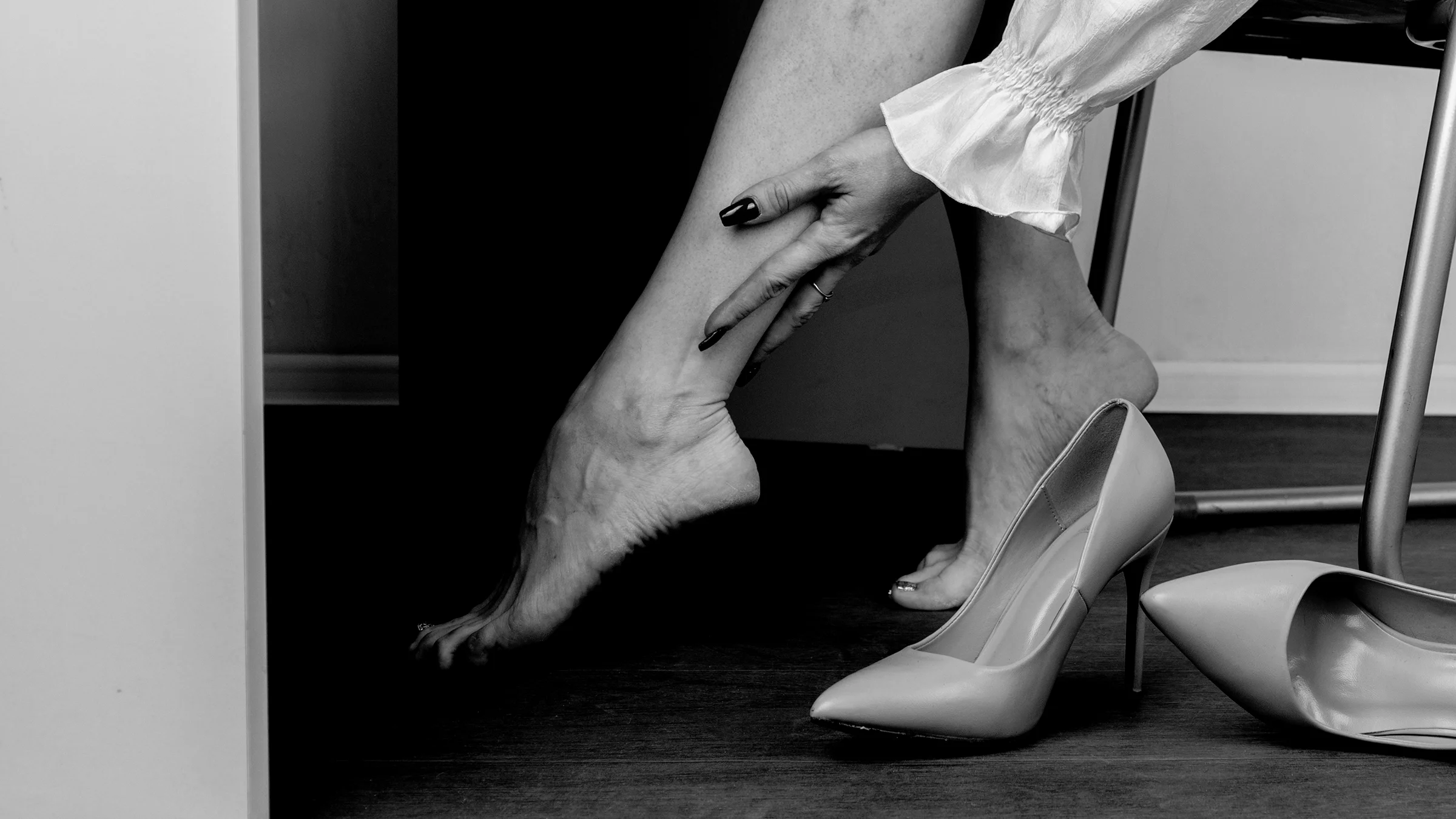 A barefoot person is reaching for their calf.