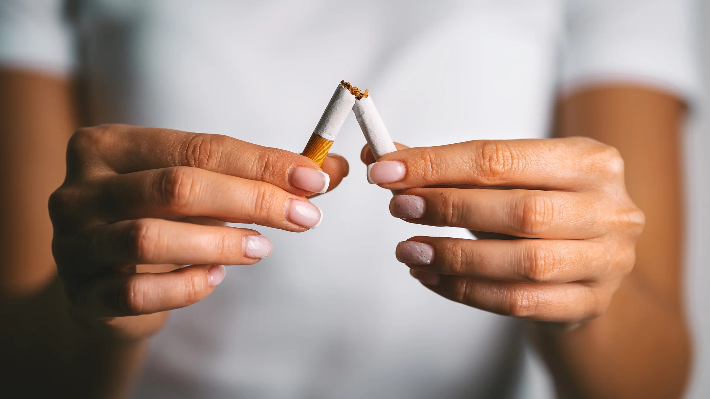 Close-up hands breaking cigarette in half