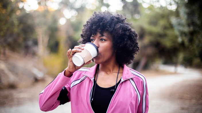 A woman walking with a cup of coffee.