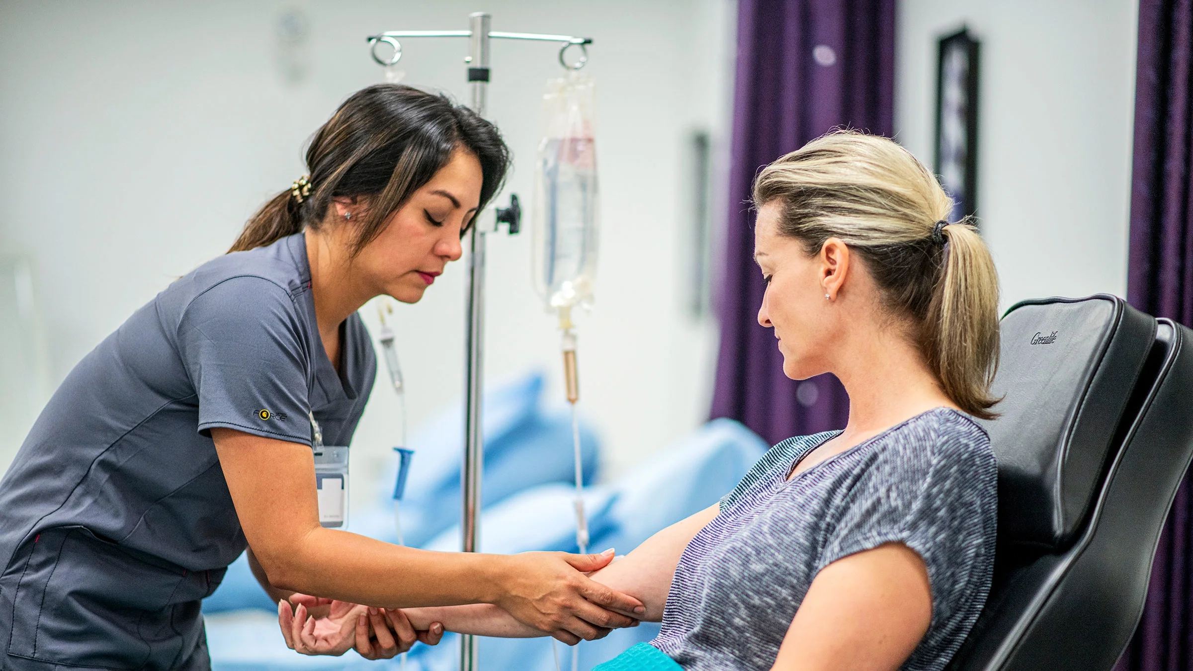 A healthcare professional administers an IV infusion for a patient.