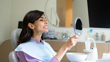 dental care: woman looking at teeth in mirror 1488786110
