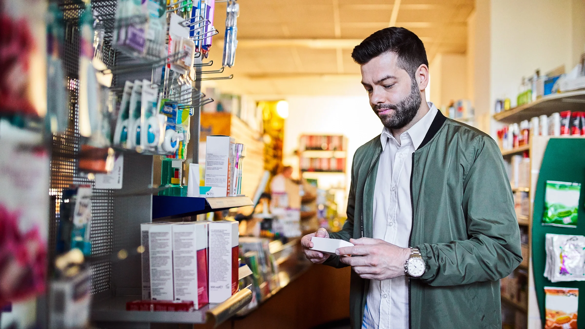 A man reads a medication’s label while shopping at the pharmacy.