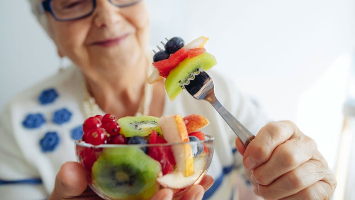 A close-up image shows an older adult with a bowl of fruit.