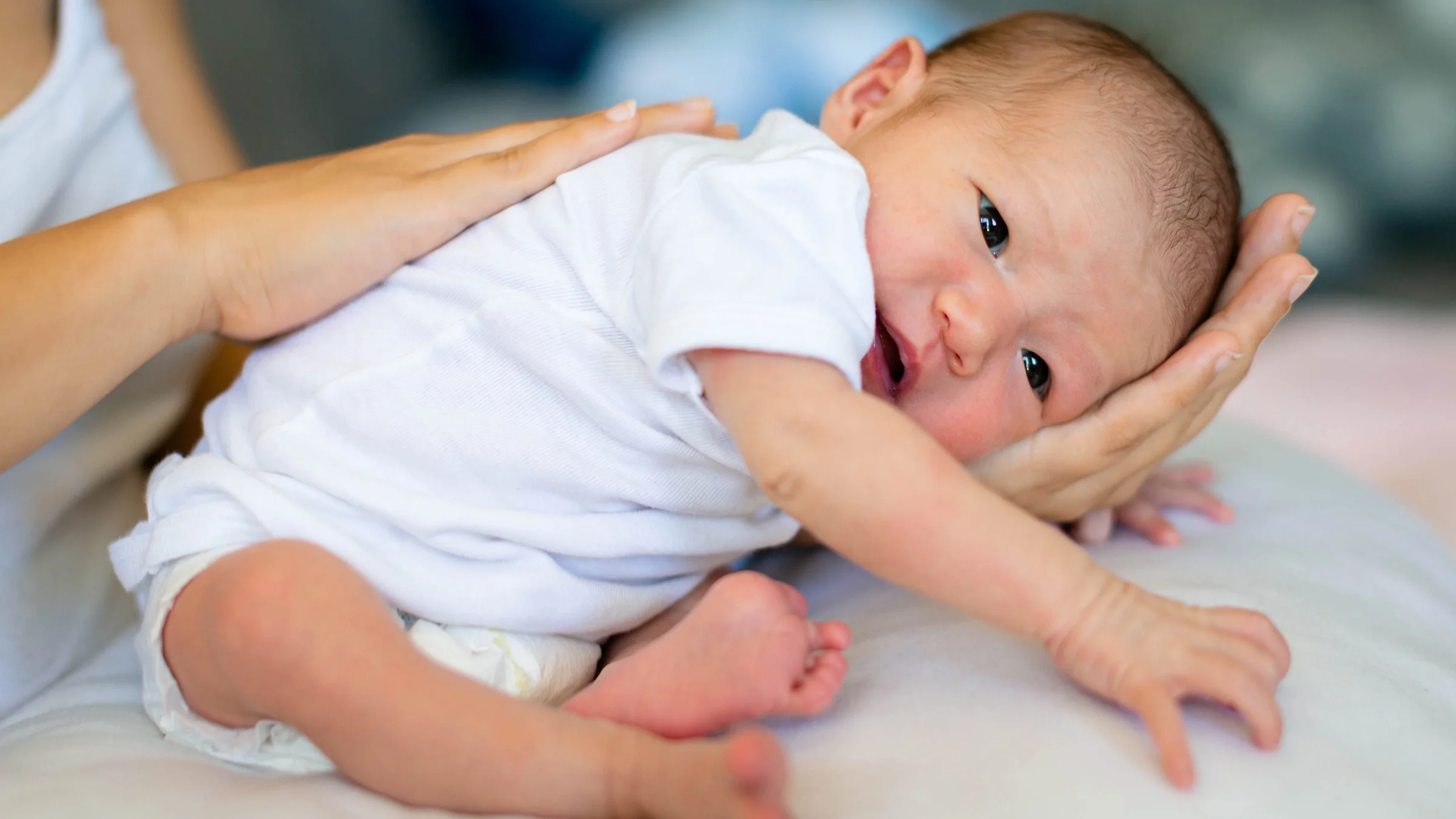 Portrait of a newborn baby resting in their mother's hands.