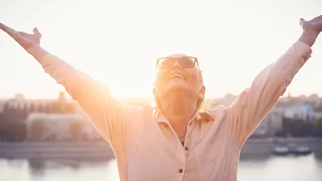 senior woman embracing the sky and sun 1343520623