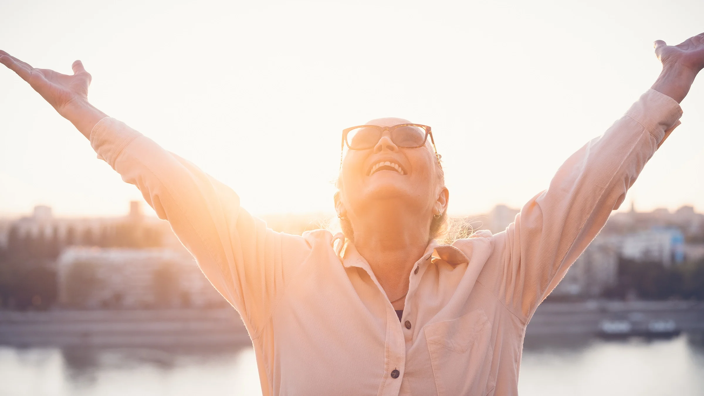 Senior woman opening her arms to the sky and sun.