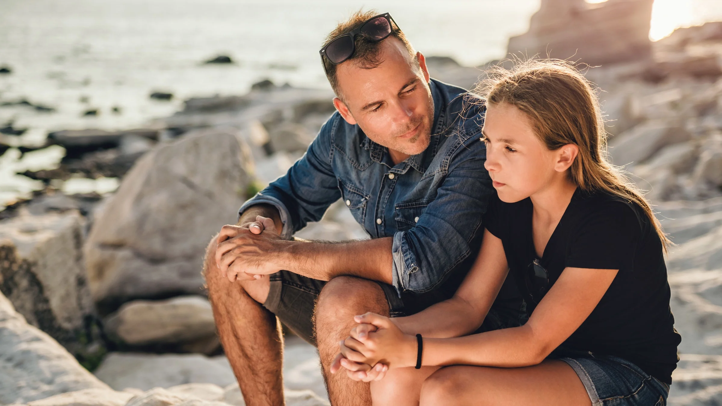 A parent and child having a conversation on the beach.