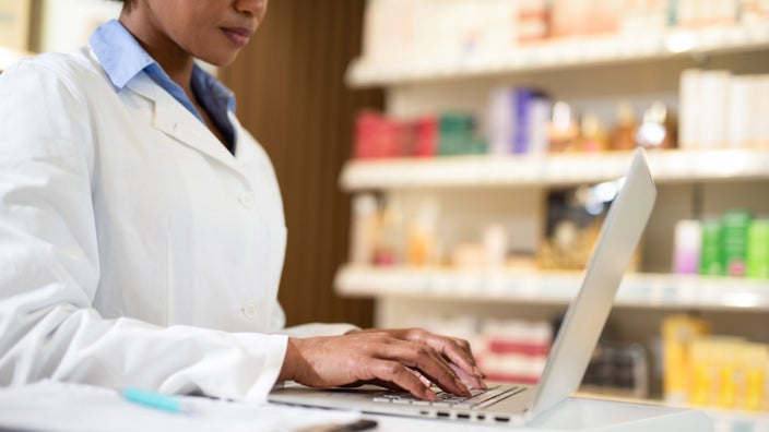 A pharmacist typing on a laptop.
