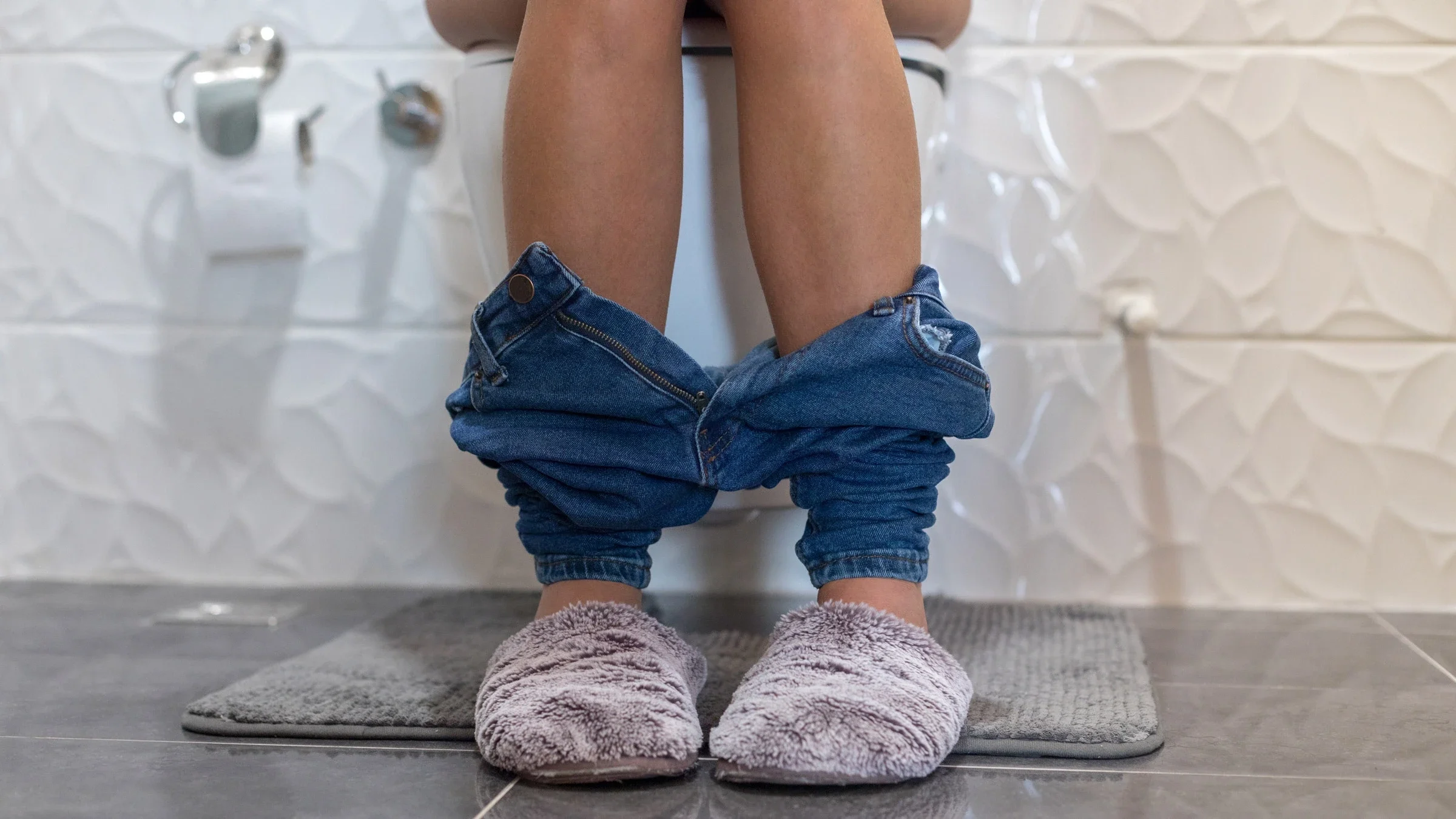 Cropped shot of legs of someone sitting on a toilet.