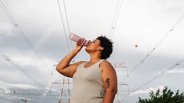 deep vein thrombosis: woman drinking water outdoors 1299829179