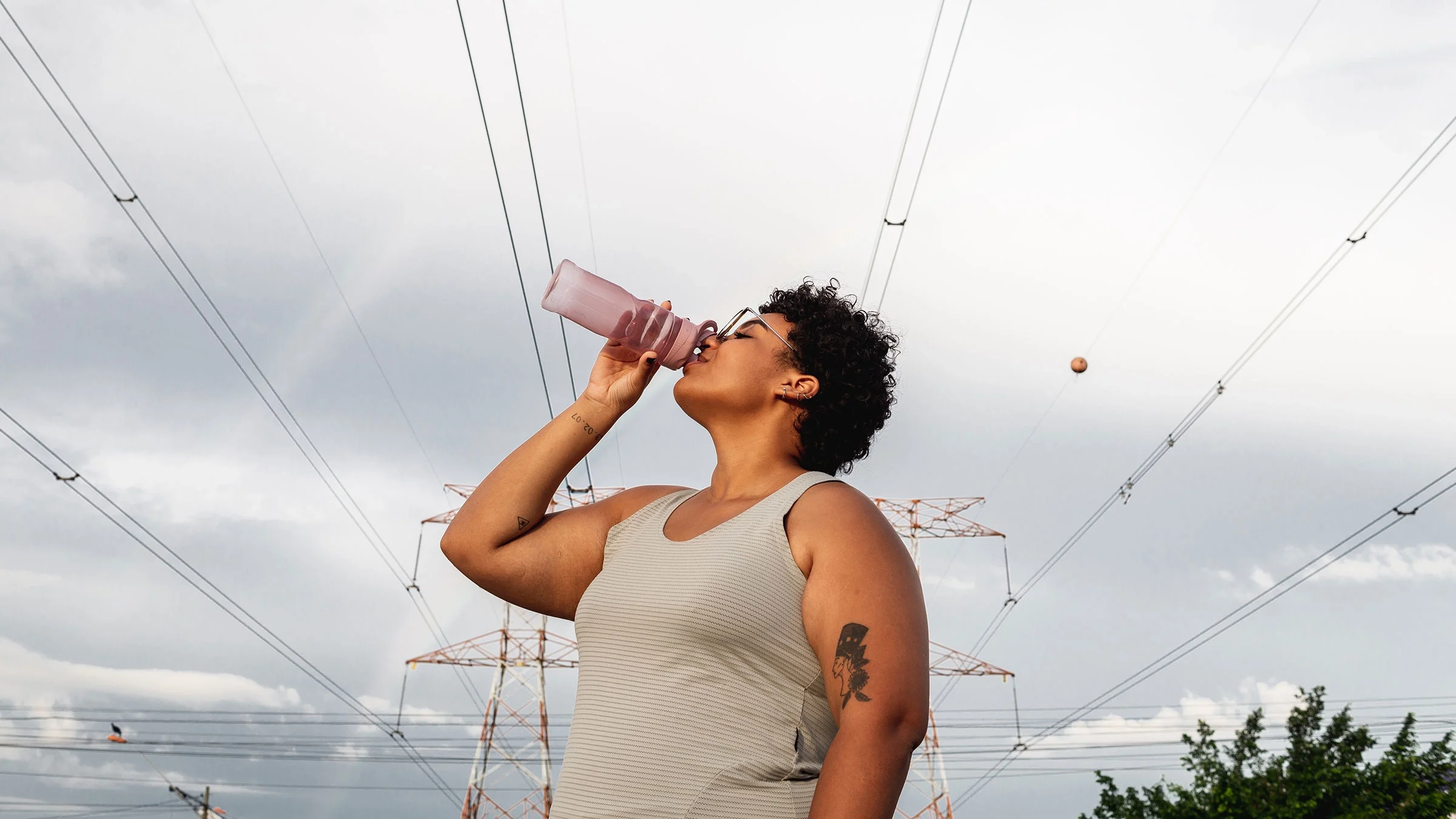 Woman drinking water while walking outdoors.