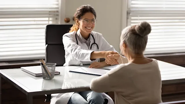 Health: Providers: doctor shaking patients hand across desk-1319103281