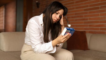 gut health: woman reading box of OTC medicine 1706520689