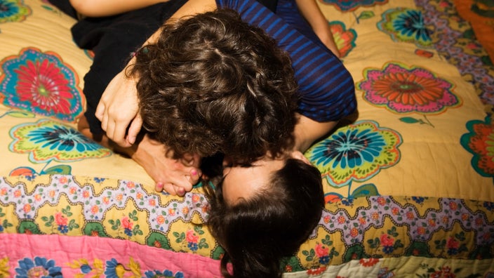 A couple kissing in bed.